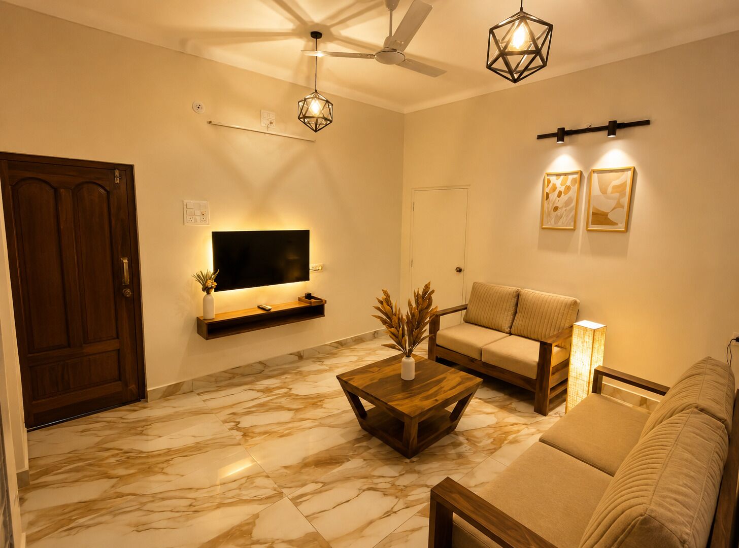 A living room with a flat-screen TV mounted on the wall, a ceiling fan, a wooden coffee table, a sofa, and a lamp.