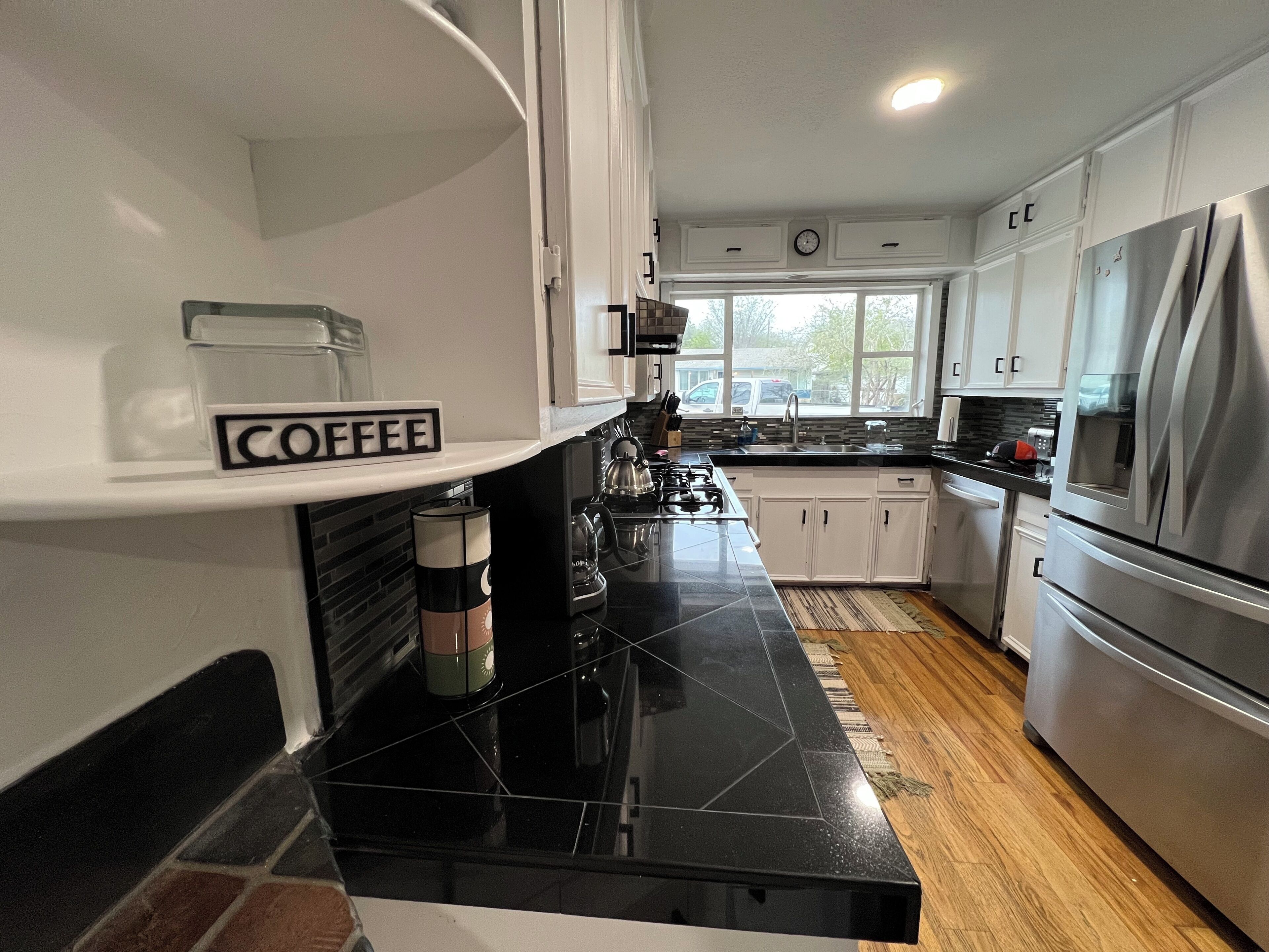 A modern kitchen with white cabinets, a black countertop, and stainless steel appliances.