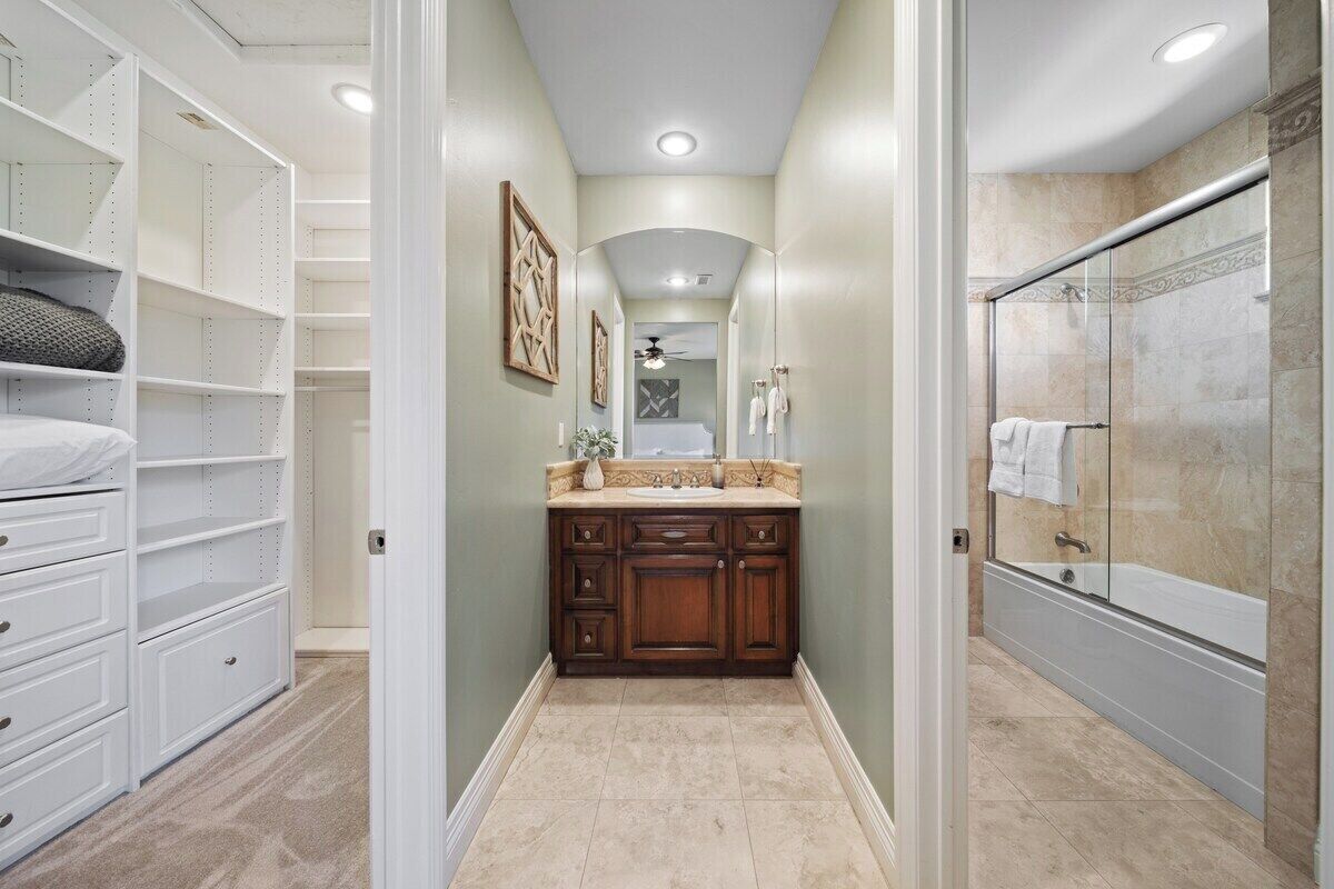 A bathroom with a walk-in shower, a vanity with a sink, and a large mirror.