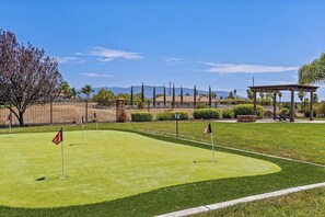 Un campo de golf con cielo despejado, una zona vallada y un pabellón.
