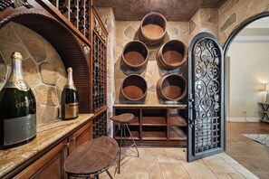 A wine cellar with wooden barrels, a wine rack, and a bar area with stools.