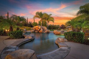 A landscaped pool area with a natural rock formation and palm trees. - Wine Country Estate w/ Pool, Spa, Theater & Golf (Temecula)