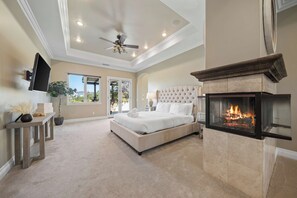 A bedroom with a bed, a fireplace, a ceiling fan, and a TV mounted on the wall. - Wine Country Estate w/ Pool, Spa, Theater & Golf (Temecula)
