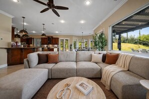 A spacious living area with a large sectional sofa, a coffee table, and a ceiling fan.