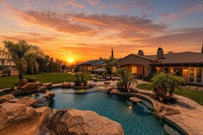 A residential property with a swimming pool, landscaped garden, and multiple houses.