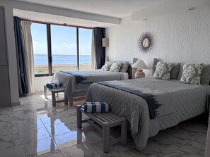 A hotel room with two beds, a view of the sea, a marble-tiled floor, and a wall-mounted mirror. - Caribbean Getaway with Beach Access and Pool, stunning view from your bedroom (Cancún)