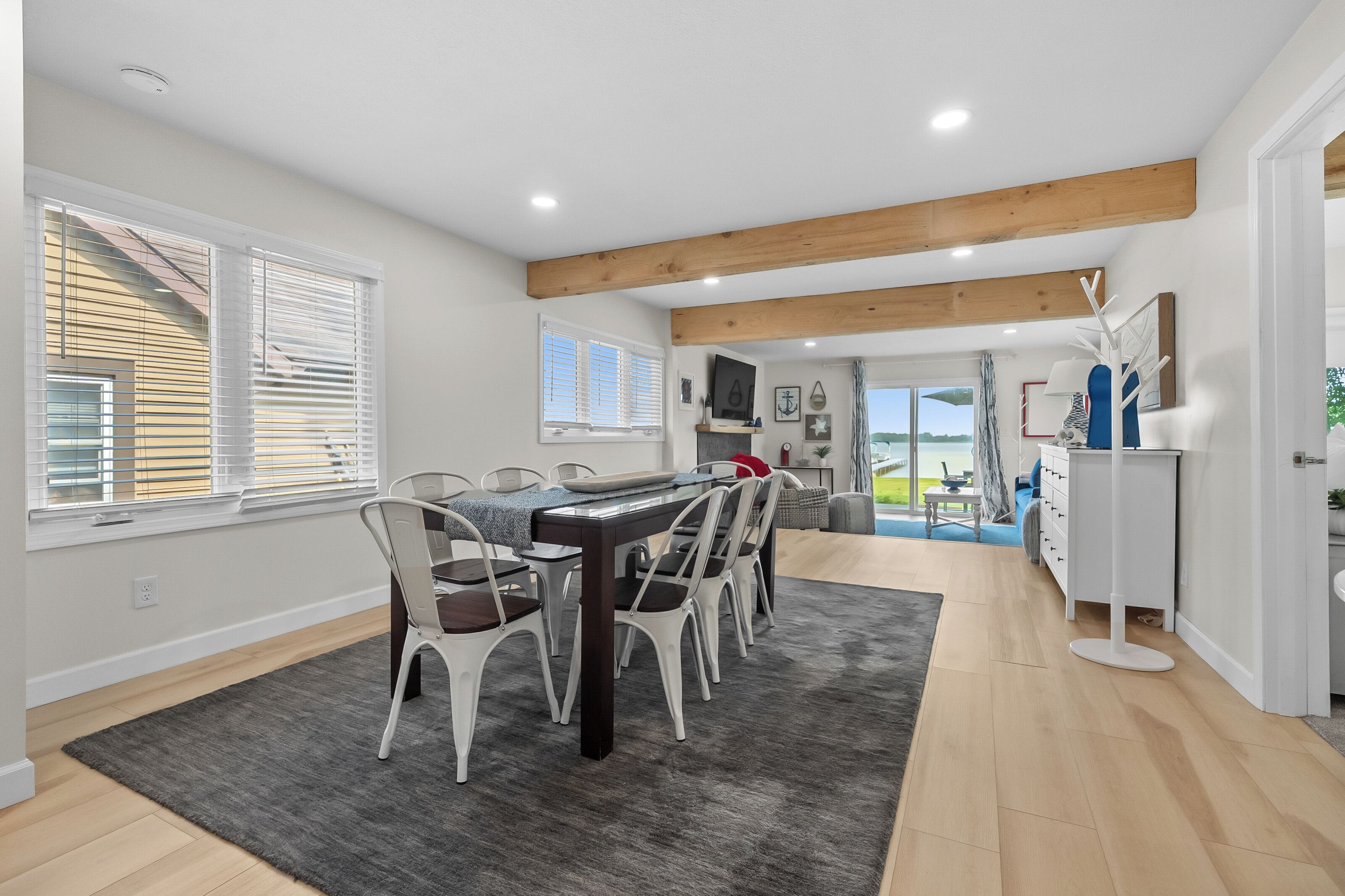 A modern kitchen with a dining area, wooden beams, and a view to the outside.