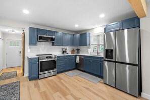 Eine moderne Küche mit blauen Schränken, Edelstahlgeräten und Holzboden.