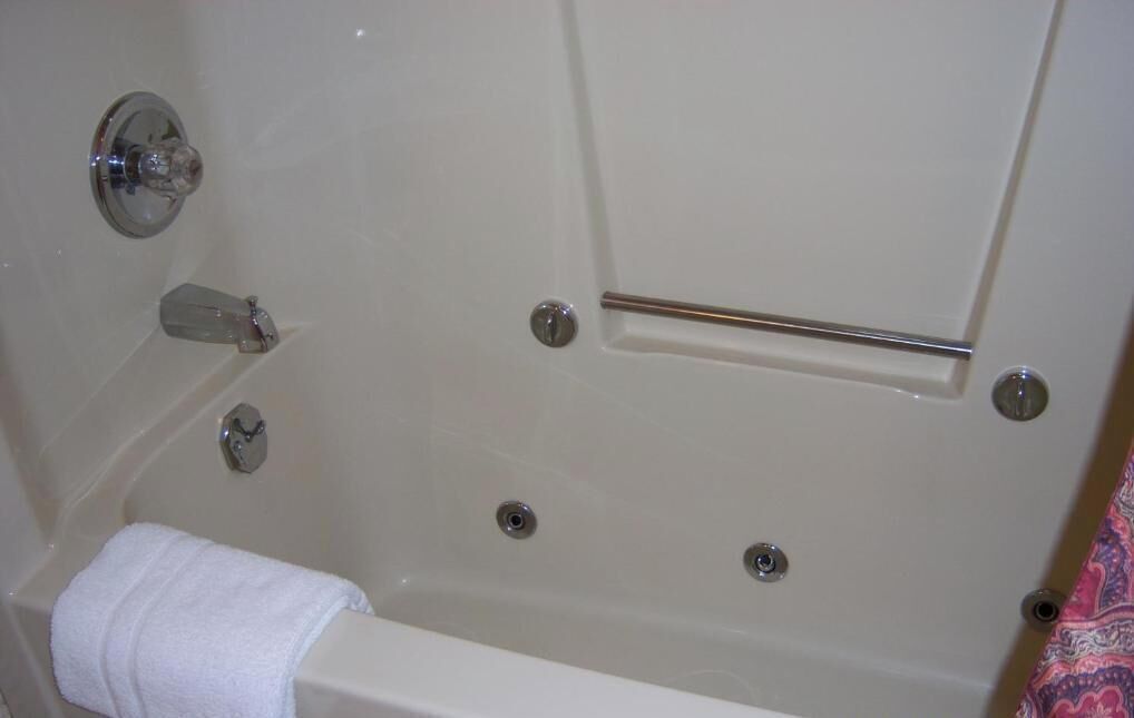 A bathtub with a towel, a grab bar, and a faucet.