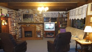 Una sala de estar acogedora con chimenea, televisor y estantería.
