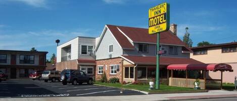 A motel with a prominent sign, a parking lot, and a building with a red roof.