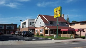 A motel with a prominent sign, a parking lot, and a building with a red roof. - Travelers Inn Motel - Eagle River Downtown (Eagle River)