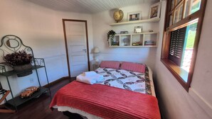A bedroom with a bed, a shelf with books and a globe, a door, and a window with shutters. - English-style country house with stunning views. (Petrópolis)