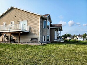 A two-story house with a balcony, a covered porch, and a well-maintained lawn. - 3-bedroom house in peaceful Fargo with cool AC breeze (Fargo)