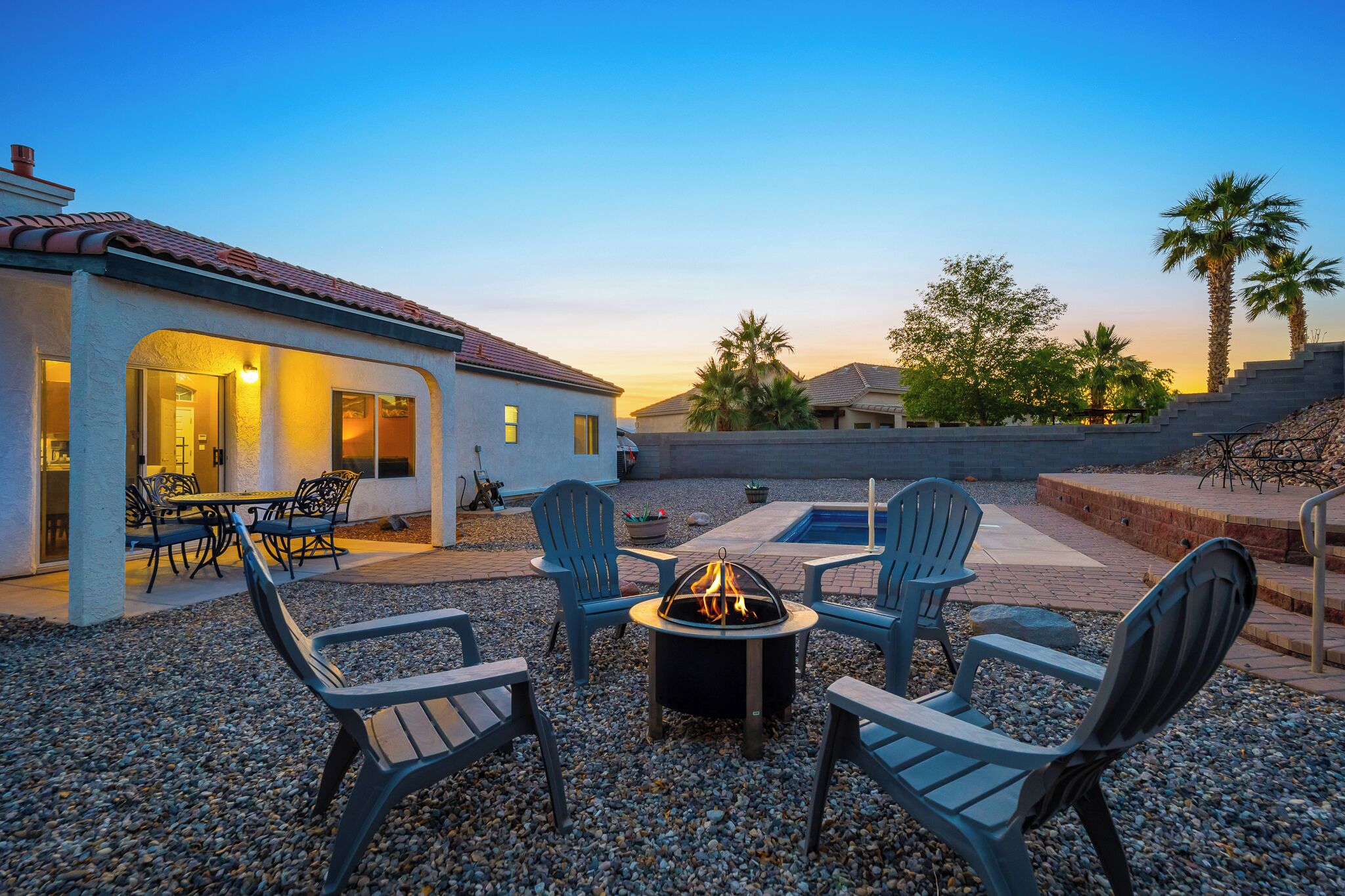 An outdoor patio area with a fire pit, seating, and a view of a residential neighborhood.