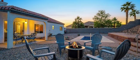 An outdoor patio area with a fire pit, seating, and a view of a residential neighborhood.