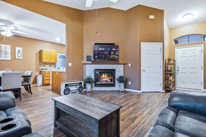 A living room with a fireplace, a kitchen in the background, and a door to the right. - Cozy desert home near the Laughlin River (Bullhead City)
