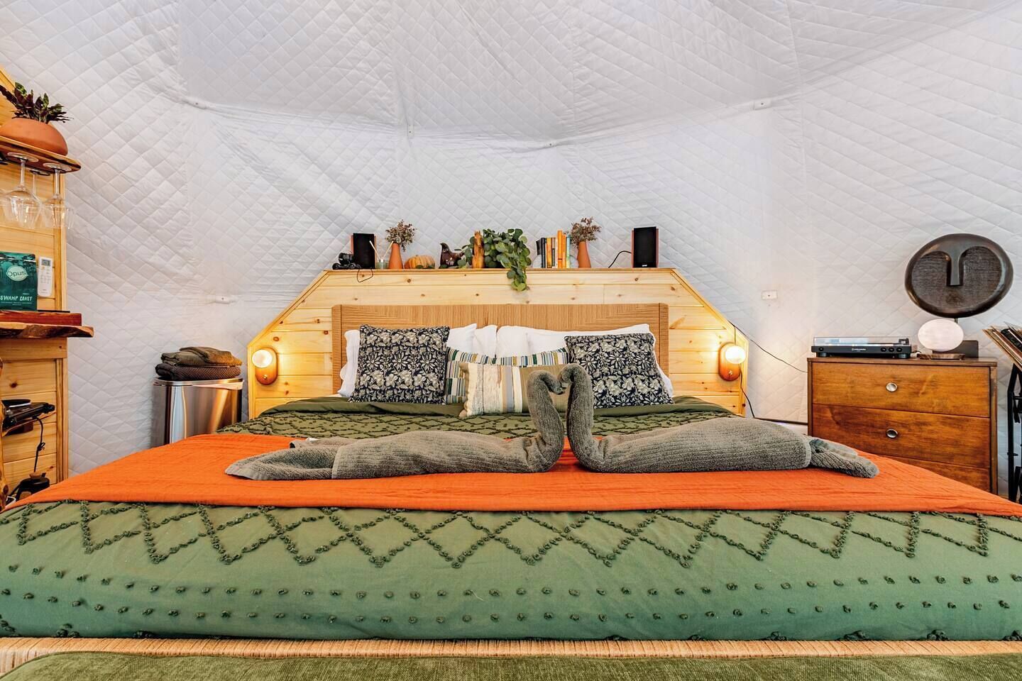 Ein gemütliches Schlafzimmer mit einem Bett, Kissen, einem Nachttisch und einer Wanduhr.