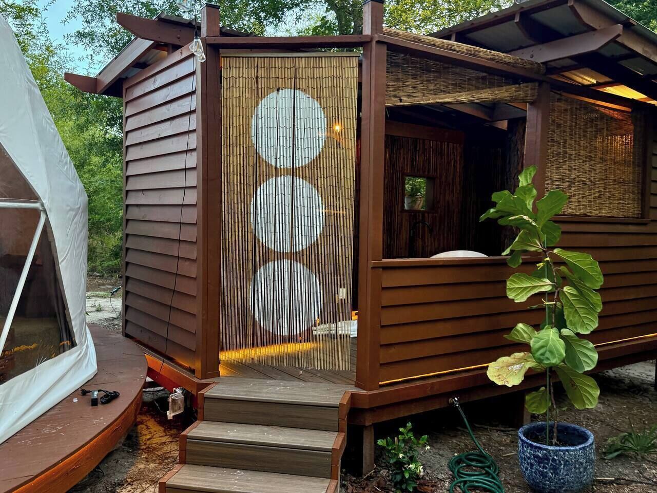 A wooden cabin with a covered porch and a sliding door with circular patterns.