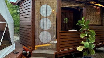 A wooden cabin with a covered porch and a sliding door with circular patterns.