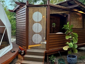 A wooden cabin with a covered porch and a sliding door with circular patterns. - Soluna GeoDome 2: Stargazing, Springs, Outdoor Tub (High Springs)