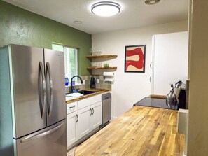 Eine Küche mit einem Edelstahl-Kühlschrank, einer Holz-Arbeitsplatte und einer Küchenpapierrolle an der Wand.