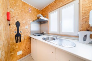 A compact kitchen with a built-in oven, a sink, and a window above the countertop.