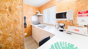 Pieni, mutta toimiva keittiönurkkaus, jossa on mikroaaltouuni, pesuallas ja Bosch-merkkinen kahvinkeitin.
