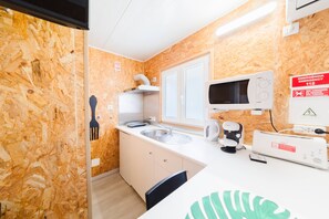 A compact kitchenette with a microwave, sink, and a Bosch coffee maker. - Bungallow - Pátio Mariano (Peniche)