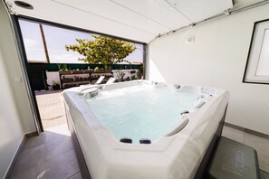 Un jacuzzi con vistas a un jardín y un edificio cercano.