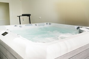 A hot tub with a control panel, a chair, and a wall-mounted heater. - Bungallow - Pátio Mariano (Peniche)