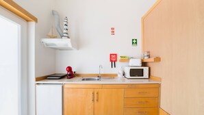 A compact kitchen with a sink, a microwave, a coffee maker, and a small refrigerator. - II Ninho - Pátio Mariano (Peniche)