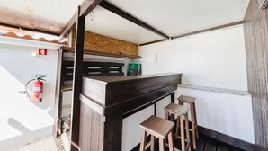 A compact kitchen with a wooden counter, stools, and a fire extinguisher. - II Ninho - Pátio Mariano (Peniche)