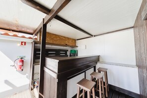 Uma cozinha compacta com bancada de madeira, banquetas e extintor de incêndio.