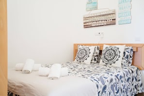 A bed with rolled towels, patterned pillows, and a wall with motivational signs. - II Ninho - Pátio Mariano (Peniche)