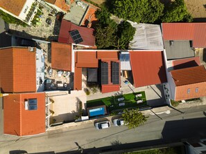 An aerial view of a residential area with multiple houses, some with red roofs, and a visible swimming pool. - II Ninho - Pátio Mariano (Peniche)