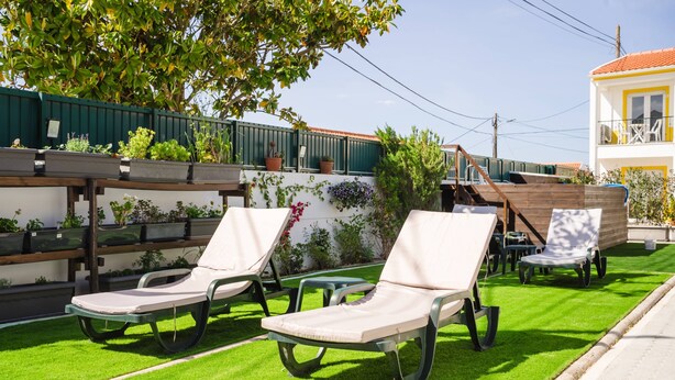 A patio area with outdoor seating and a green lawn. - II Ninho - Pátio Mariano (Peniche)