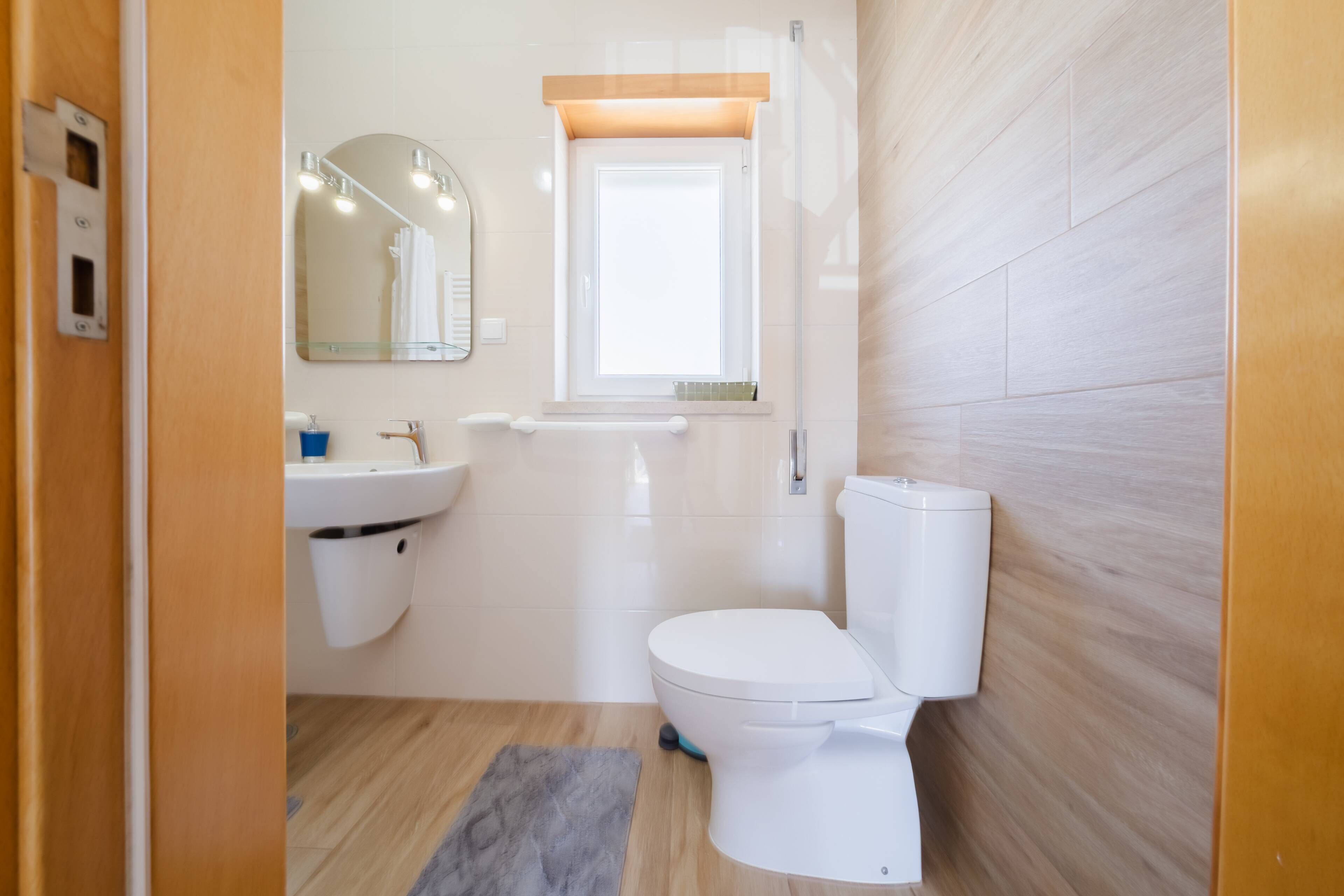 A modern bathroom with a toilet, sink, and mirror.