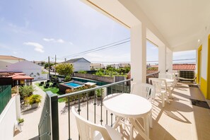 Ein Balkon mit Pool, Sitzgelegenheit im Freien und Blick auf angrenzende Häuser.