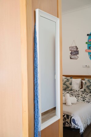 A room with a bed, a wall-mounted mirror, and a wall decoration. - III Ninho - Pátio Mariano (Peniche)