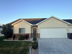 A two-story residential building with a garage, a front door, and a driveway.