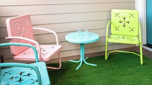 A room with a colorful geometric wall art, a small round table, and two chairs with a green and pink color scheme. - 2BR/2BA Hot Tub Suite • Coat of Many Colors (Sevierville)