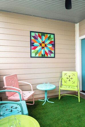 A room with a colorful geometric wall art, a small round table, and two chairs with a green and pink color scheme. - 2BR/2BA Hot Tub Suite • Coat of Many Colors (Sevierville)