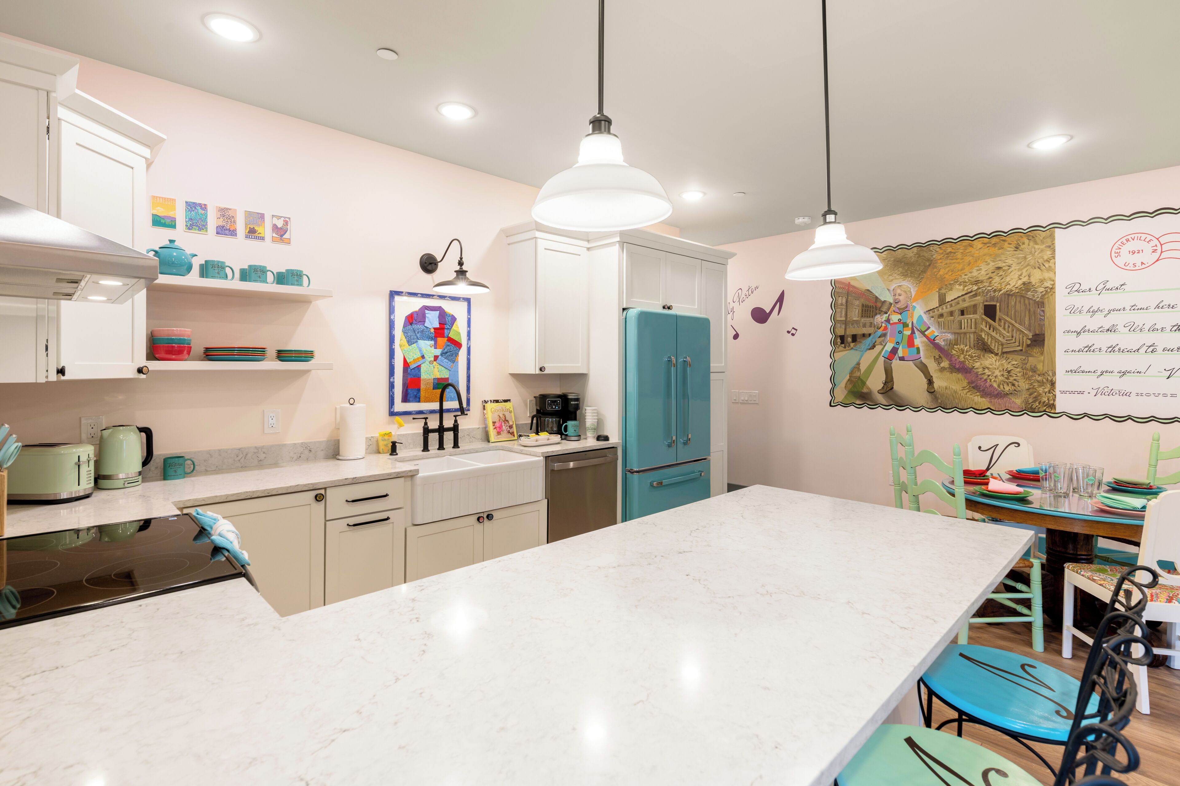 Une cuisine moderne avec des meubles blancs, un réfrigérateur de couleur turquoise et un plan de travail en marbre.