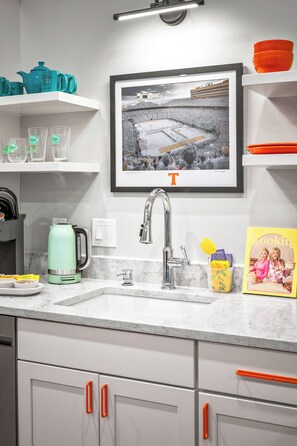 A kitchen with a marble countertop, a framed photograph above the sink, and a coffee maker. - 1BR Hot Tub Suite • Tennessee (Sevierville)