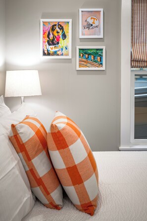 A bed with orange and white checkered pillows, a white lamp, and two framed artworks on the wall. - 1BR Hot Tub Suite • Tennessee (Sevierville)