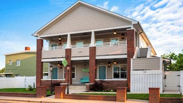 A two-story building with a balcony, a front porch, and a garage door.