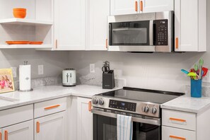 A kitchen with white cabinets, a stainless steel microwave, a stove, and a toaster. - 1BR Hot Tub Suite • Tennessee (Sevierville)