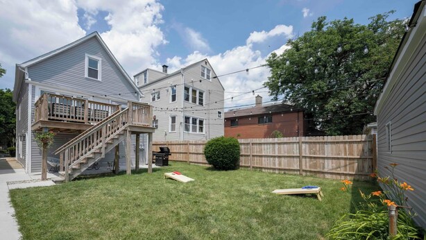 Patio trasero residencial con una terraza de madera, una parrilla y un pequeño jardín.