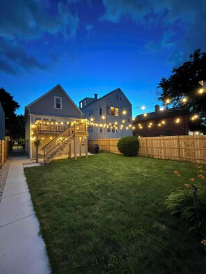 A two-story house with a covered porch and a staircase leading to the upper level. - Fully Furnished 2BR. 5-min walk to train. In-unit laundry. Parking Available (Chicago)